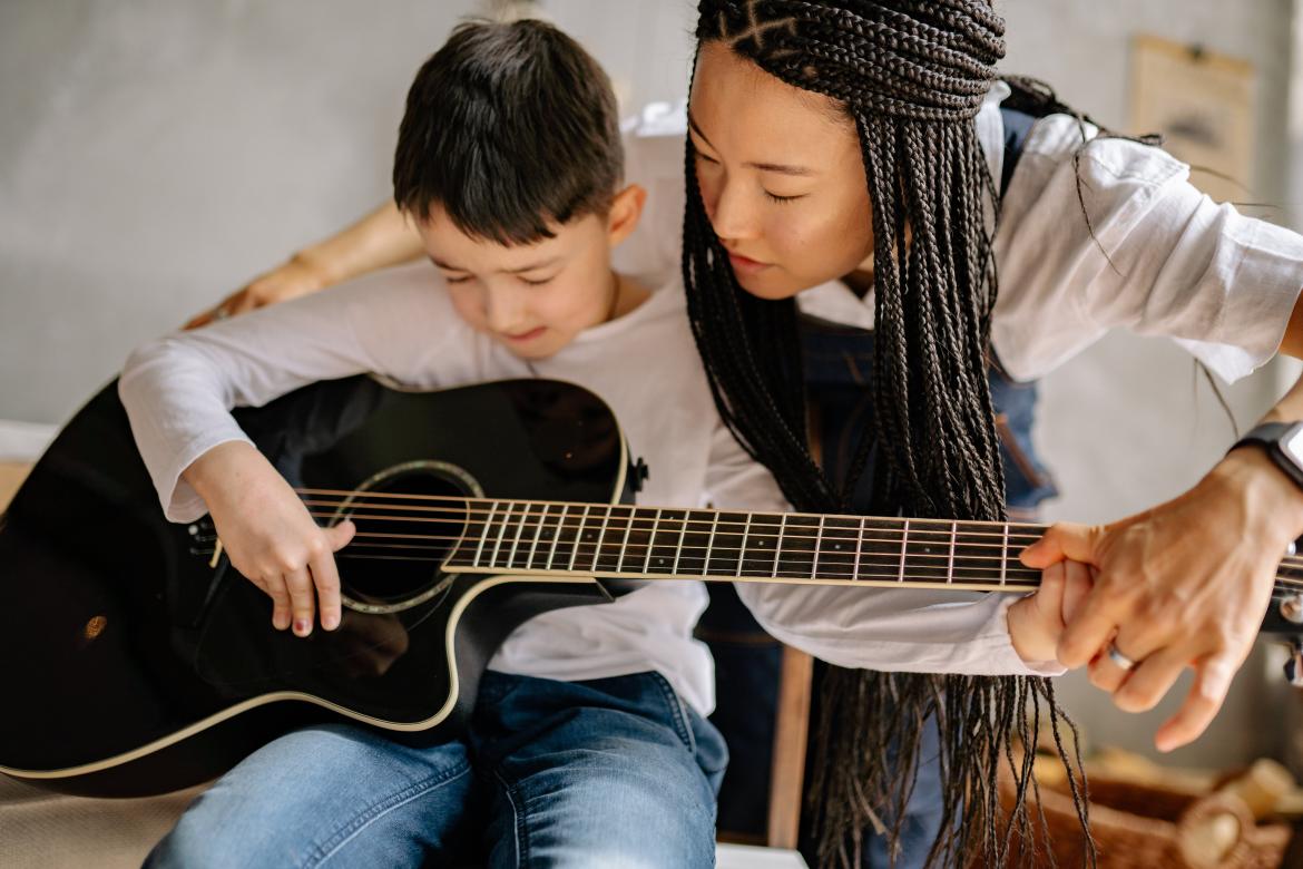 Teacher teaching young child guitar