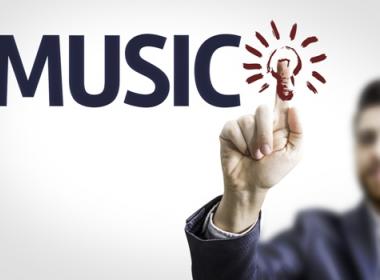 Man putting his finger on a light bulb image next to the word music