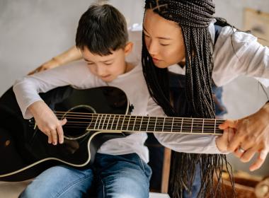 Teacher teaching young child guitar